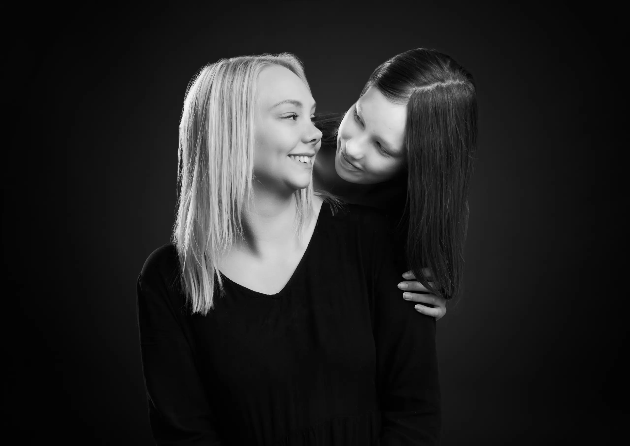 Søskendebillede i sort hvid af en blond og en brunhåret pige
